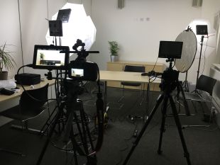 Video production equipment surrounding an empty desk and chair 